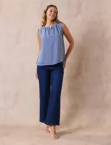 Blusa celeste sin mangas en crepe con cuello a la base con frunce, apertura ojal y botón.