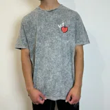 Remera gris con efecto acid wash y estampa en la espalda de una figura femenina sosteniendo una manzana.