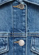 Chaqueta corta de jean celeste con cuello camisero, cierre frontal con botones metálicos, bolsillos de parche con solapa en el pecho y mangas largas con puños abotonados.
