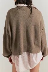 Cárdigan negro de silueta oversized, confeccionado en hilo de algodón suave con terminaciones acanaladas, escote en V, hombros caídos y mangas largas amplias.