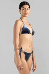 Bombacha de bikini azul de terciopelo con textura a rayas finas, corte triángulo clásico con tiras laterales ajustables y detalle de charm floral.