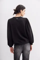 Buzo negro de algodón con cuello redondo y mangas largas abullonadas. Presenta apliques de flores bordadas con lentejuelas.