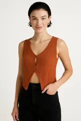 Top sin mangas color crema, de punto crochet con rayas verticales, cuello en v y cierre frontal con broches.