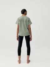 Remera de manga corta con calce oversize y cuello redondo. Confeccionada en tejido de poliéster, presenta un diseño de hombros caídos y un sutil estampado tonal en el pecho.