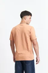 Remera color durazno de manga corta con cuello redondo y estampado frontal con texto en recuadro.