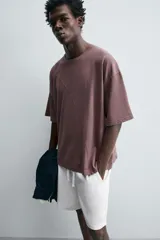 Camiseta color marrón con costura curva en el frente, corte holgado, cuello redondo y mangas cortas.