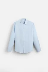 Camisa celeste de corte regular fit, cuello italiano, manga larga con puños abotonados y cierre frontal con botones.