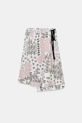 Falda midi de tiro alto confeccionada en hilatura con lino, color blanco con estampado geométrico en tonos marrones y rojizos. Cierre frontal cruzado con lazada a contraste en color negro.