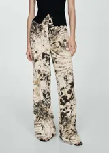 Pantalón wideleg con estampado animal print en tonos beige, marrón y negro. Tiene tiro medio y cierre de cremallera invisible en el lateral.