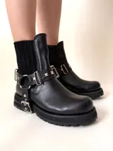 Botín negro de cuero vacuno con elásticos laterales y estribo desmontable con apliques y herrajes metálicos color níquel.