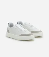 Championes urbanos blancos de material sintético con detalles en gris y negro. Presentan punta redonda, cordones, perforaciones para mayor respirabilidad y suela bold.