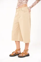 Bermuda de jean color beige, tiro medio, con bolsillos delanteros y traseros.