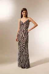 Vestido largo de poliéster con estampado animal print de cebra en blanco y negro. Tiene breteles finos, escote drapeado y corte al cuerpo.