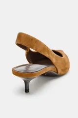 Zapato destalonado de serraje color camel, con punta fina y tira trasera elástica. Posee un tacón bajo tipo kitten heel.