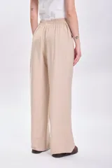 Pantalón de vestir beige de corte palazzo, con cintura alta y bolsillos laterales.