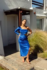 Vestido largo de terciopelo azul eléctrico, con un hombro descubierto, una manga larga, abertura lateral y falda con frunces.