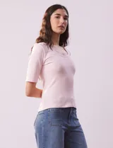 Remera rosa de tejido rib, con cuello redondo y manga corta.