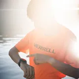Remera deportiva naranja de poliéster, con mangas cortas y logo de la marca Merrell estampado en el pecho.