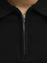 Polo negro de punto con cierre de cremallera, cuello polo y mangas cortas.