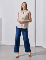 Camisa sin mangas de lino a rayas verticales azules y blancas, con cuello con solapa, escote en V, abertura central con botones y bolsillo en el pecho.
