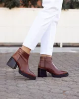 Botines de cuero marrón, hechos a mano en Uruguay, con plataforma delantera y taco ancho y alto de color negro. Presentan un detalle de textura de piel de reptil en la parte superior del talón y cierre lateral con cremallera.