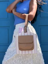 Matero con forma de balde, confeccionado en material símil cuero beige con estampado de rayas verticales en verde militar. Posee bolsillo frontal, asa de mano y correa larga desmontable.