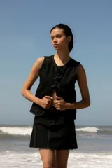 Chaleco de denim negro sin mangas con cuello redondo y costuras en contraste. Presenta un parche de cuero marrón en la parte posterior con el logo de la marca Be Ganesha. Confeccionado en tejido de algodón.