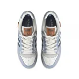 Zapatillas urbanas Adidas Rivalry Low, color blanco con detalles en celeste y azul marino. Confeccionadas en cuero y gamuza, con las tres tiras características de la marca en los laterales.