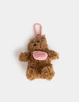 Llavero con forma de oso de peluche marrón con cartera tejida rosa y gancho metálico rosa.