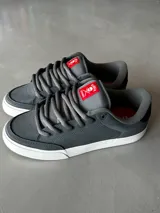 Championes CIRCA modelo AL 50 PRO, color gris con detalles en negro y rojo. Fabricados con materiales de alta calidad, puntera triple cosida, lengüeta acolchada con parche con el logo y ojales metálicos.