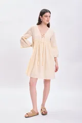 Vestido corto amarillo con escote en V con cordones y mangas 3/4 acampanadas.