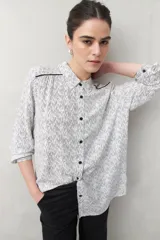 Camisa de manga larga con estampado paisley en tonos azul y blanco, cuello camisero y cierre frontal con botones.
