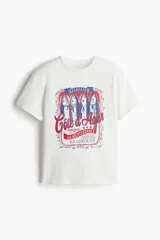 Remera blanca de algodón con cuello redondo y mangas cortas. Estampado frontal con diseño de lata de sardinas con texto en francés y detalles en rojo y azul.