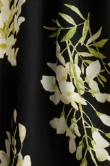 Vestido corto negro con estampado floral blanco y amarillo, de breteles finos, escote corazón, cuerpo entallado, espalda fruncida, cintura marcada con elástico y falda con vuelo.