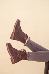 Bota de cuero gamuzado, con cordones, doble hebilla en la parte superior y cierre lateral interno.