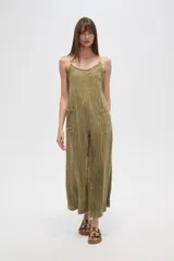 Mono de algodón negro, estilo lencero, con tirantes finos, escote en V y bolsillos frontales. El calce es holgado y presenta un cordón ajustable en la cintura.