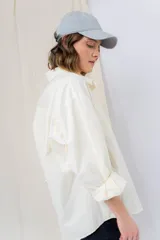 Camisa color crema de algodón liviano, calce oversize, con cuello camisero, cierre abotonado, mangas largas con opción de arremangado y dos bolsillos frontales con solapa.