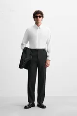 Camisa de vestir verde oscuro, corte slim fit, con cuello italiano, mangas largas con puños abotonados y cierre frontal con botones.