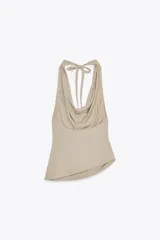 Top color beige confeccionado en algodón 100% con efecto teñido. Presenta cuello halter con lazada y escote drapeado. El bajo tiene un acabado asimétrico.