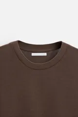 Camiseta marrón de punto de algodón, corte recto, cuello redondo y manga corta con terminaciones en rib.