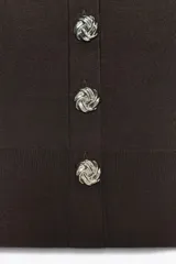 Chaqueta de punto marrón oscuro con cuello redondo y manga larga abullonada. Cierre frontal con botones metálicos plateados con diseño de rosa.