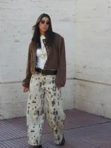 Campera bomber oversize color chocolate, con cierre frontal y detalles de ojales metálicos en la solapa. Confeccionada en gamuza, tiene mangas abullonadas con puños elásticos.