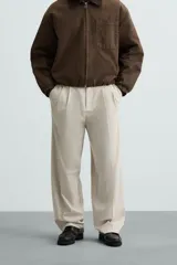 Pantalón de vestir color beige, corte wide fit, con cintura elástica, pliegues frontales, bolsillos laterales y traseros de vivo.