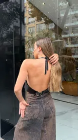 Top halter negro de efecto cuero, ajustado al cuerpo, con detalle de pespunte vertical central y borde festoneado en el escote y sisas.