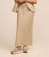 Conjunto color beige compuesto por una falda midi de lino y viscosa con lazo en la cintura y un chaleco sin mangas con botones. Incluye un bolso tote beige.