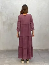 Vestido largo color morado, con escote en V, mangas largas y corte escalonado.