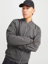 Campera bomber gris oscuro de Jack & Jones, con cuello y puños elastizados, cierre frontal con cremallera, bolsillos laterales con cremallera y bolsillo en la manga izquierda.