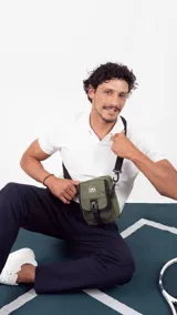 Morral verde militar con cierre, bolsillo delantero con presilla y broche de plástico, bolsillos internos y correa larga regulable.