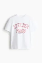 Remera blanca de algodón con estampado rojo que dice "Atelier Paris 115 Av. France, Paris".