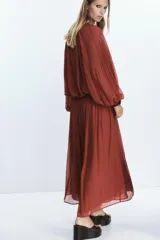 Falda midi color ladrillo, de tiro alto, con plisado fino y estampado de pequeños lunares. Incluye cinturón fino del mismo tejido y forro interior.